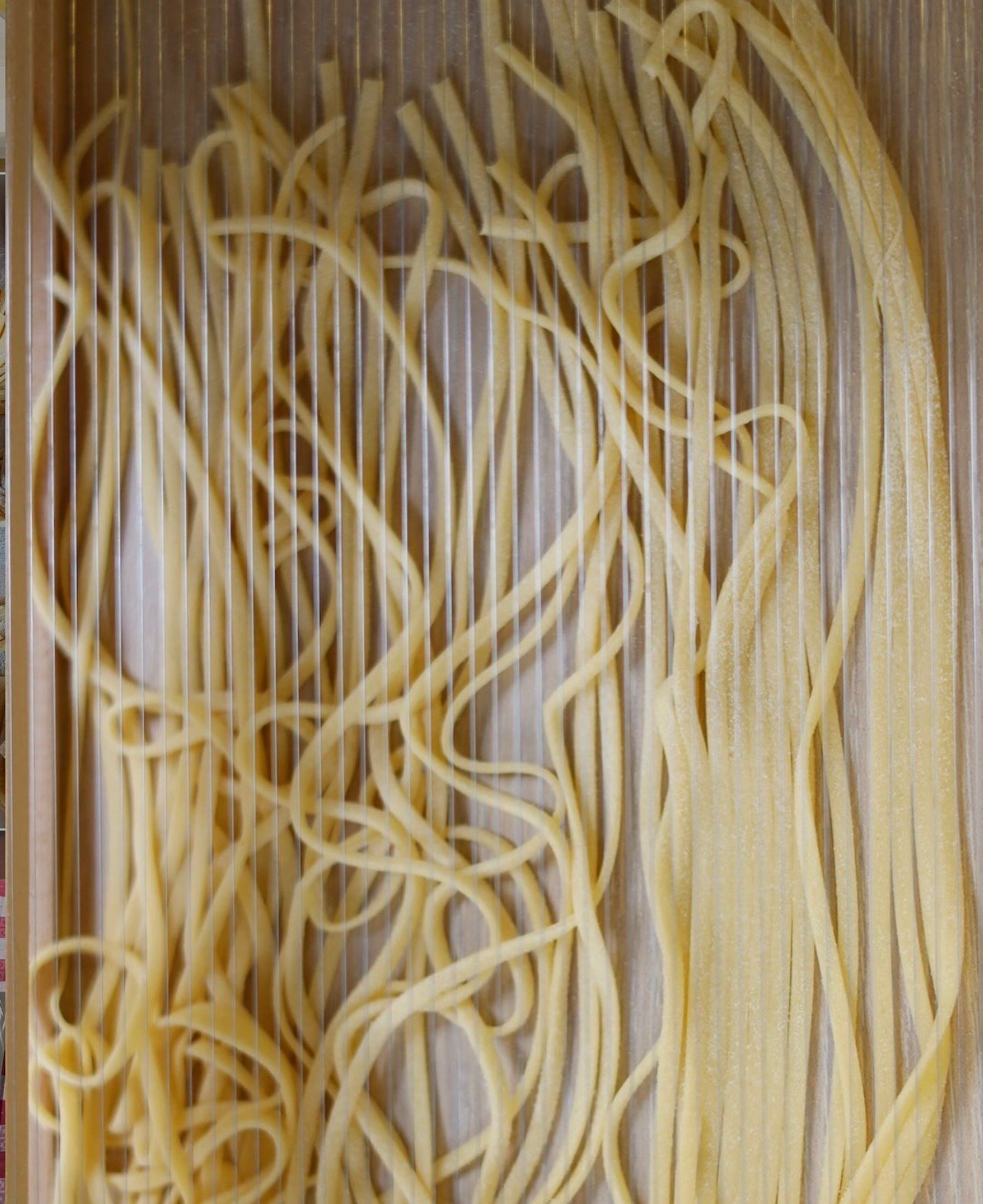 Strands of fresh pasta laid over a wooden chitarra