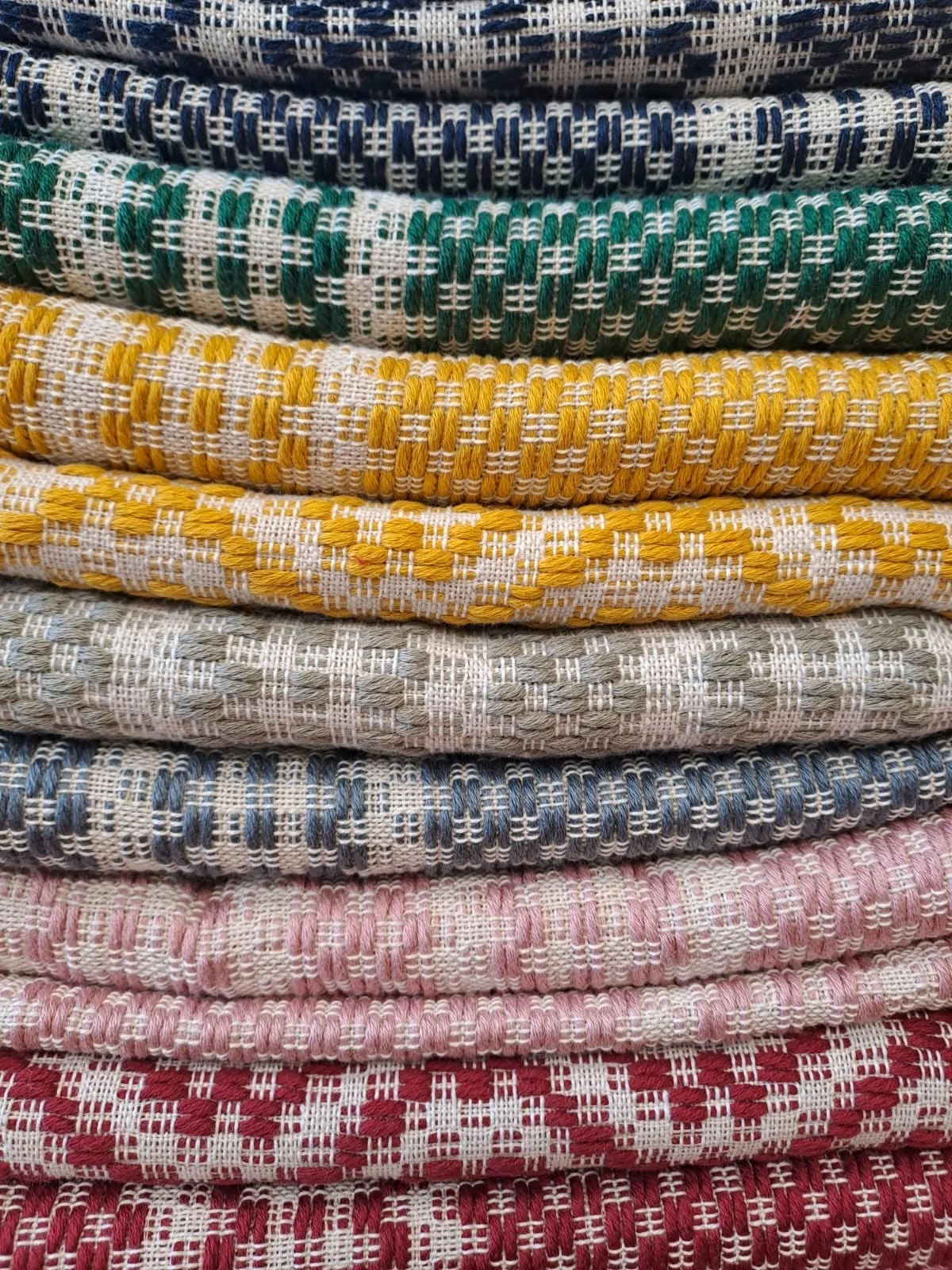 Folded Casoli textiles with traditional Abruzzese patterns in mustard, green, blue, pink and red