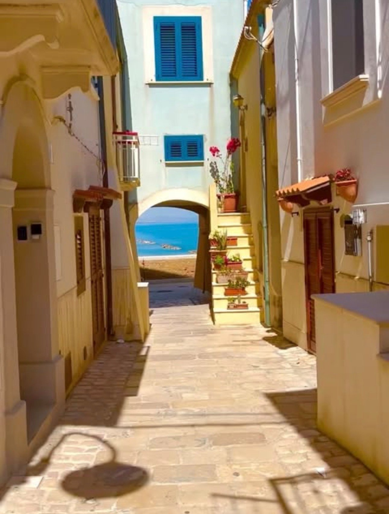 A sunlit lane with blue shutters and a glimpse of the sea in Termoli